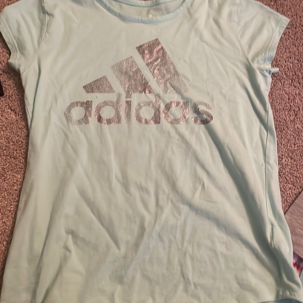 It is an Adidas t shirt and it is teal with sparkles as the logo.